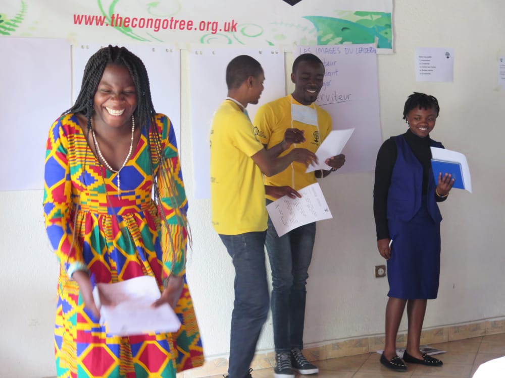 Person in a colourful dress smiling. Three people stood behind her.